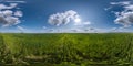 spherical 360 hdri panorama among green grass farming field with clouds on blue sky with sun in equirectangular seamless Royalty Free Stock Photo