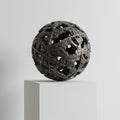 A spherical bronze sculpture with an intricate openwork design sits atop a white Royalty Free Stock Photo
