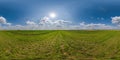 spherical 360 hdri panorama among green grass farming field with clouds on blue sky with sun in equirectangular seamless Royalty Free Stock Photo