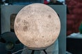 Spherical moon-textured lamp on stand, in an indoor setting, possibly a tech workshop or office, with cool tones and muted blue Royalty Free Stock Photo