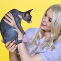 Sphinx kitten is in hands of young woman cosplay elf with blonde hair. Yellow background Royalty Free Stock Photo