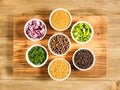 Spice black pepper, fenugreek, masala, allspice, chopped red onion, green onion, fennel in white bowls on brown wood background