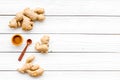 Spice and condiment. Ground ginger in small bowl near ginger root on white wooden background top view copy space Royalty Free Stock Photo