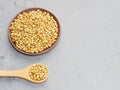 Spice coriander Coriandrum sativum seeds in clay plate and wooden spoon on gray concrete background