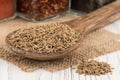 Spice cumin in wooden spoon and an old white wooden table.