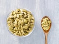 Spice green cardamom Elettaria cardamomum in transparent bowl and wooden spoon on gray concrete background closeup