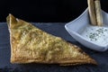 Spiced lamb samosa accompanied by yogurt sauce on a slate plate