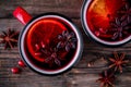 Spiced Pomegranate Apple Cider Mulled Wine Sangria in red mugs on wooden background.