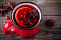 Spiced Pomegranate Apple Cider Mulled Wine Sangria in red mugs on wooden background.