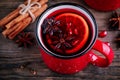 Spiced Pomegranate Apple Cider Mulled Wine Sangria in red mugs on wooden background.