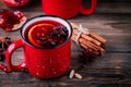 Spiced Pomegranate Apple Cider Mulled Wine Sangria in red mugs on wooden background.