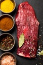 Spices in bowls and raw flank steak