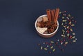 Spices cinnamon sticks, cardamom pods, star anise, sugar, nutmeg, coriander and pepper seeds in brown ceramic cup on a black slate Royalty Free Stock Photo