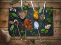 Spices and herbs in spoons dark background, top view