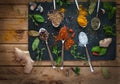 Spices and herbs in spoons dark background, top view