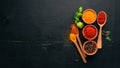 Spices and herbs on a wooden board. Pepper, salt, paprika, basil, turmeric. On a black wooden chalkboard.