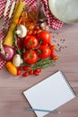 Spices, pasta and vegetables around notebook.