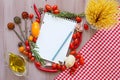 Spices, pasta and vegetables around notebook.