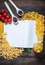 Spices, pasta and vegetables around notebook on a wooden table. Mockup