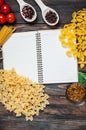 Spices, pasta and vegetables around notebook on a wooden table. Mockup