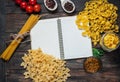 Spices, pasta and vegetables around notebook on a wooden table. Mockup