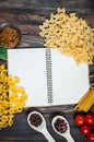 Spices, pasta and vegetables around notebook on a wooden table. Mockup