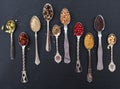 Variety of colorful spices in spoons on black stone background, top view Royalty Free Stock Photo