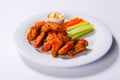 Spicy BBQ buffalo chicken wings sitting on plate garnished with carrot and celery sticks with blue cheese dipping sauce Royalty Free Stock Photo