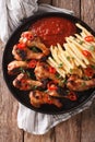 Spicy BBQ chicken wings with french fries and sauce close-up. Vertical top view Royalty Free Stock Photo