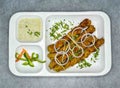 Spicy beef chicken seekh kabab with raita and onion in white tray traditional pakistani BBQ food top view on grey background Royalty Free Stock Photo