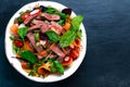 Spicy Beef Meat Salad with vegetables on blue stone.