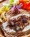 Spicy bifteki, frikadelle or frikkadel meatballs with minced beef and lamb with pita bread, tzatziki dip, vegetables salad and Fre