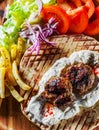 Spicy bifteki, frikadelle or frikkadel meatballs with minced beef and lamb with pita bread, tzatziki dip, vegetables salad and Fre