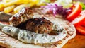 Spicy bifteki, frikadelle or frikkadel meatballs with minced beef and lamb with pita bread, tzatziki dip, vegetables salad and Fre