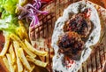 Spicy bifteki, frikadelle or frikkadel meatballs with minced beef and lamb with pita bread, tzatziki dip, vegetables salad and Fre