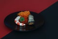 Red caviar, shrimp, spicy carrots and eggplant stuffed with carrots and walnuts on black clay plate on border of contrasting