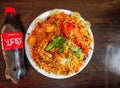 Spicy chicken biryani with potato half litter coke bottle 500 ml, onion and lemon slice served in plate isolated wooden background