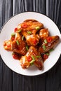 Spicy chicken wings in teriyaki sauce served with green onions and chili pepper close-up on a plate. Vertical top view Royalty Free Stock Photo