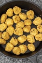 Spicy coated southern fried chicken bites in a cast iron frying pan.