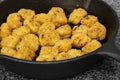 Spicy coated southern fried chicken bites in a cast iron frying pan.