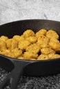 Spicy coated southern fried chicken bites in a cast iron frying pan.