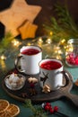 Spicy cranberry tea in two white mugs on a wooden board on a concrete green background in Christmas style. Merry Christmas concept