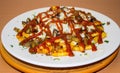 Spicy fast food: French fries with cheddar cheese, chili and chicken fillet, close-up sauce on a plate. Background Royalty Free Stock Photo