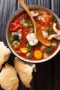 Spicy fish soup with eel, tomatoes and other vegetables close-up in a bowl served with bread. Vertical top view Royalty Free Stock Photo