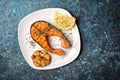 Spicy fried red fish salmon steak on white plate with garlic and lemon Royalty Free Stock Photo