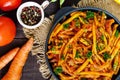 Spicy green beans stewed with onions, carrots in tomato sauce. Serve on a cast-iron frying pan on a dark wooden background. Royalty Free Stock Photo