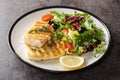 Spicy grilled cod fish fillet with fresh vegetable salad and leaf lettuce mix and lemon close-up in a plate. Horizontal Royalty Free Stock Photo