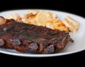 Spicy hot grilled spare ribs from BBQ served on a plate with paprika scalloped potatoes. Royalty Free Stock Photo