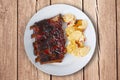 Spicy hot grilled spare ribs from BBQ top view served on a plate with paprika scalloped potatoes on rustic wood table. Royalty Free Stock Photo