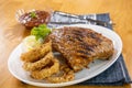 Spicy hot grilled spare ribs from a summer BBQ served with a hot chili pepper and fresh tomatoes on an old vintage wooden cutting Royalty Free Stock Photo